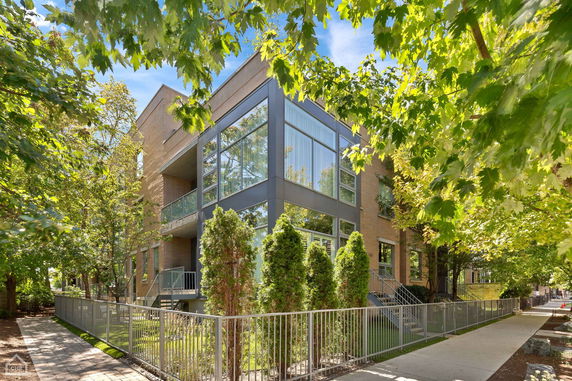 Front view of a modern three-story building with large glass windows and brick facade.