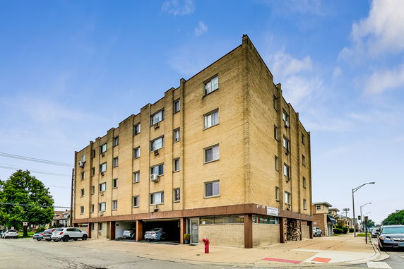 Front view of a multi-story brick building with parking at the ground level.