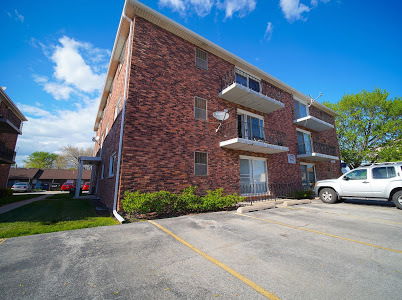 Front view of a multi-story brick apartment building with balconies.
