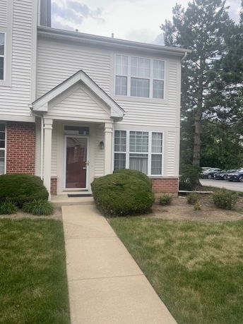 Front view of a two-story house with a small porch and brick accents.