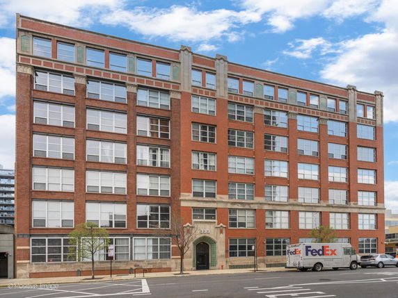 Front view of a multi-story brick building with large windows.
