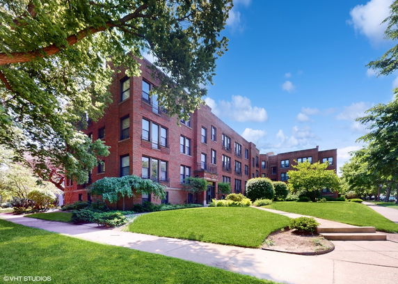 Front view of a multi-story brick building with surrounding greenery.