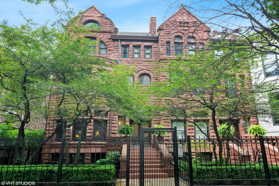 Front view of a multi-story brick building with arched windows and a gated entrance.