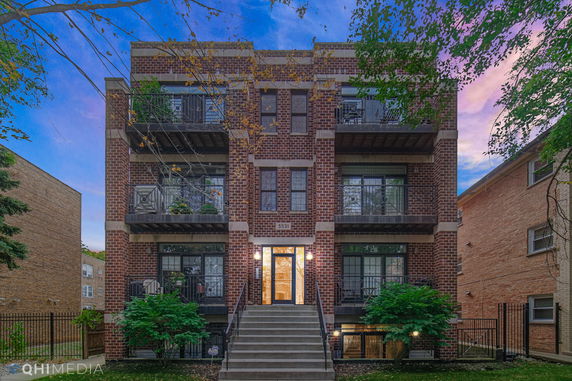 Front view of a multi-story brick building with balconies and a staircase.
