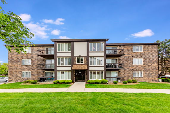 Front view of a multi-story apartment building with brick siding and balconies.