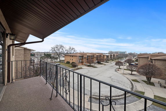 View from a balcony overlooking a residential street with multiple buildings.