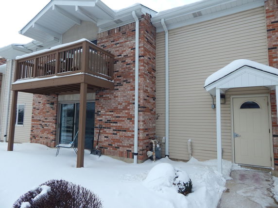 Front view of a house with a balcony and snow-covered ground.
