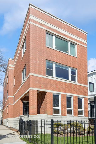 Front view of a three-story brick building with large windows.