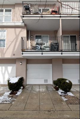 Outdoor parking area in front of a townhouse with balconies above.