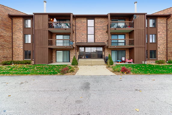 Front view of a three-story apartment building with brick exterior and balconies.