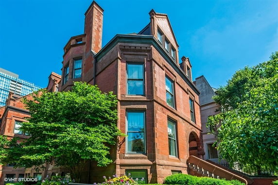 Front view of a three-story brick house with decorative windows and chimneys.