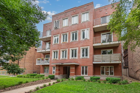 Front view of a multi-story brick apartment building with balconies.