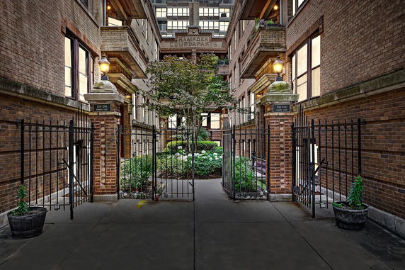 Front view of a multi-story brick apartment building with entrance gate.