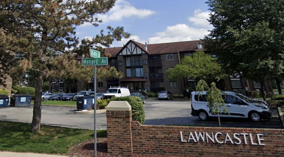 Front view of a multi-story apartment building with a parking area.
