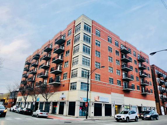 Front view of a multi-story brick apartment building with balconies.