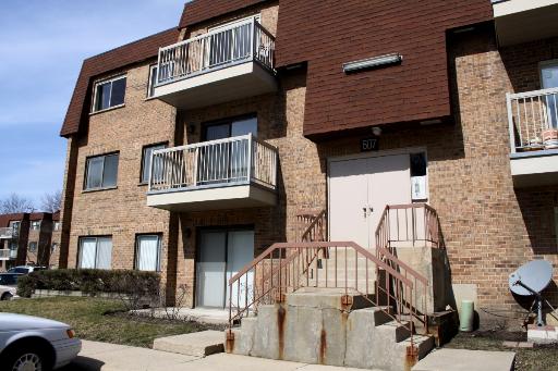 Front view of a multi-story brick apartment building with balconies.