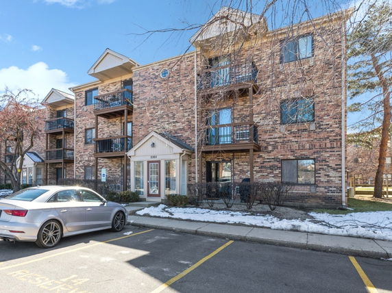 Front view of a multi-story brick apartment building with balconies.