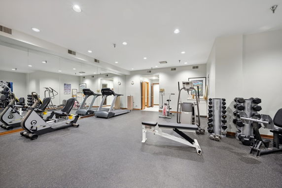 Indoor gym area with exercise equipment and wall mirrors.