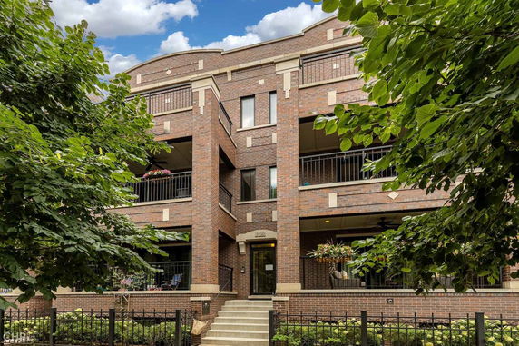 Front view of a multi-story brick building with balconies and a central entrance.