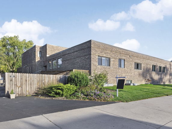 Front view of a brick building with multiple windows and a wooden fence.