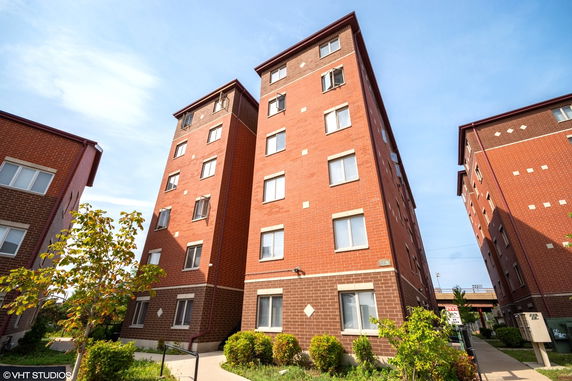 Front view of a multi-story brick apartment building with multiple windows.