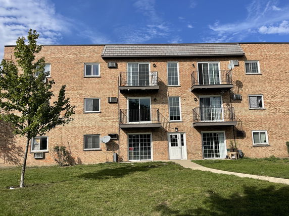 Front view of a multi-story brick apartment building with balconies.