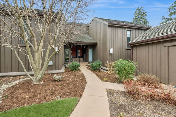 Front view of a house with brown wooden siding and an entrance pathway.