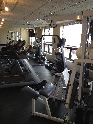Gym area with various exercise equipment including treadmills and weight machines.
