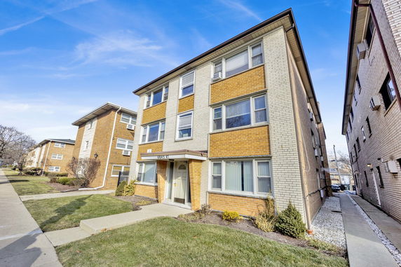 Front view of a three-story residential building with brick exterior.
