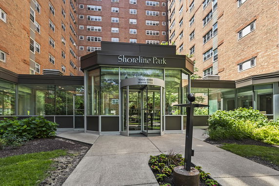 Front view of a high-rise building entrance with glass facade and revolving door.