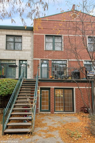 Front view of a multi-story brick townhouse with external stairs and large windows.