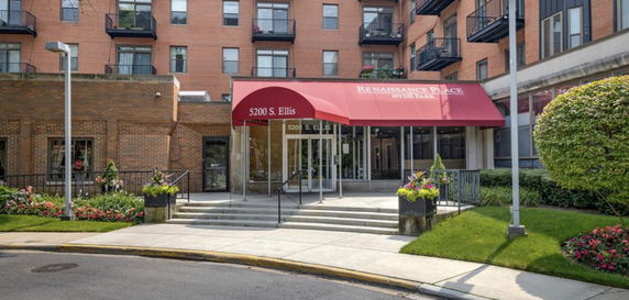 Front view of a multi-story brick building with a red entrance awning.