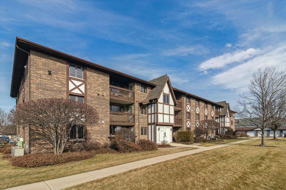 Front view of a three-story brick apartment building with Tudor-style elements.