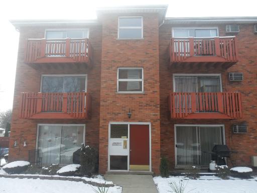 Front view of a three-story building with brick facade and balconies.