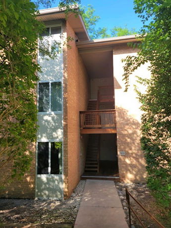 Front view of a multi-story building with visible staircases and large windows.