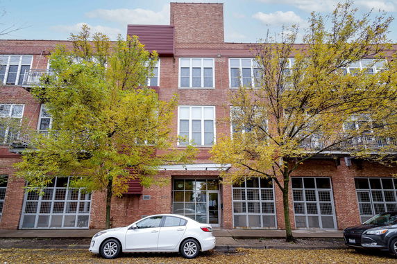 Front view of a three-story brick building with large windows and a central entrance.