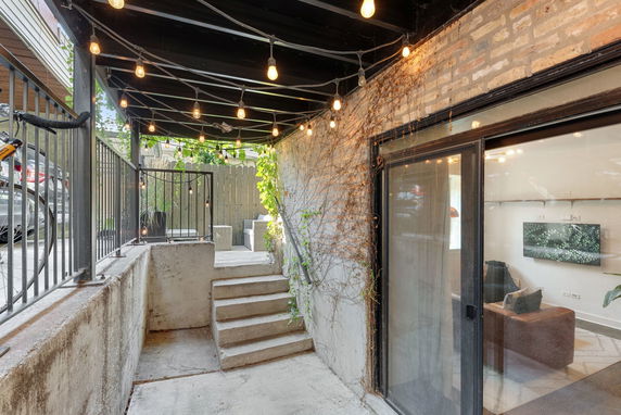 Outdoor area with string lights, steps leading to a higher level, and a sliding glass door entrance.