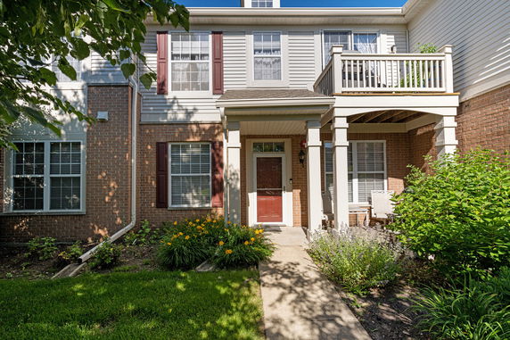 Front view of a two-story house with a small balcony and brick facade.