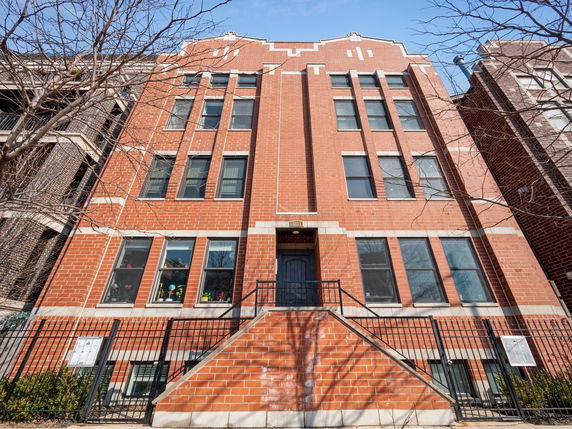 Front view of a multi-story brick building with multiple windows.