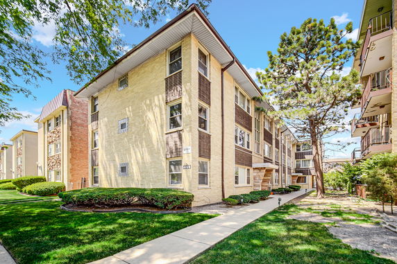 Front view of a multi-story residential building with brick exterior and large windows.