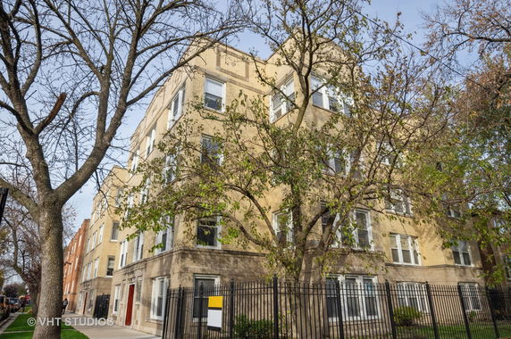 Front view of a multi-story apartment building with beige brick facade.