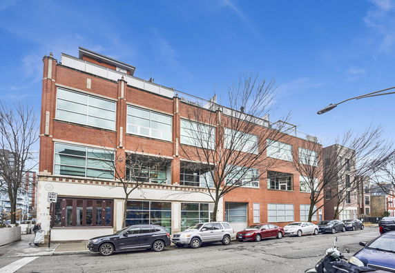 Front view of a multi-story brick building with large windows.