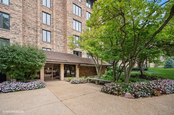 Front view of a multi-story brick building with a landscaped entrance.