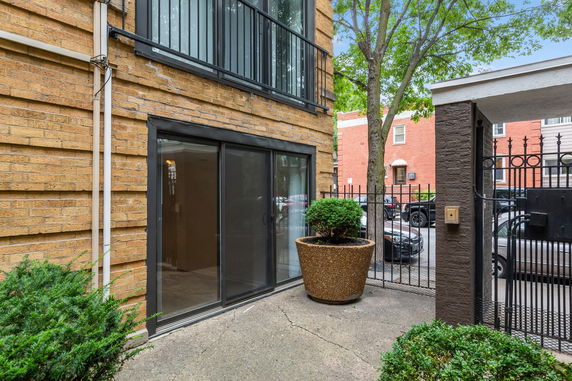 Exterior view of a building with a sliding glass door and metal railing above.