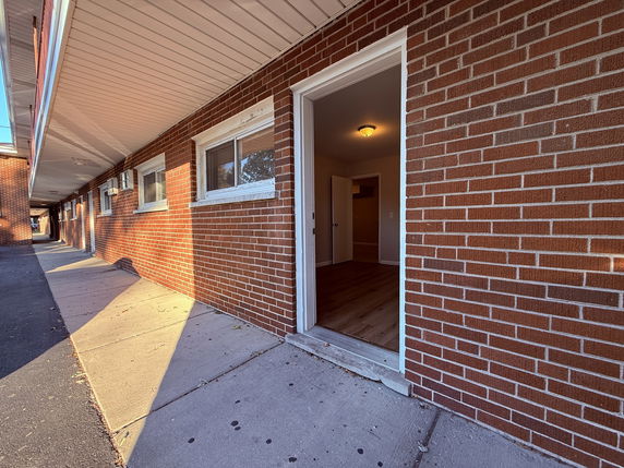 Side view of a brick building with an open entrance door.