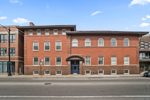 Front view of a two-story brick building with symmetrical windows and an arched entrance.