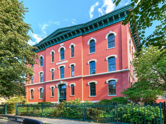 Front view of a multi-story red brick building with ornate windows.