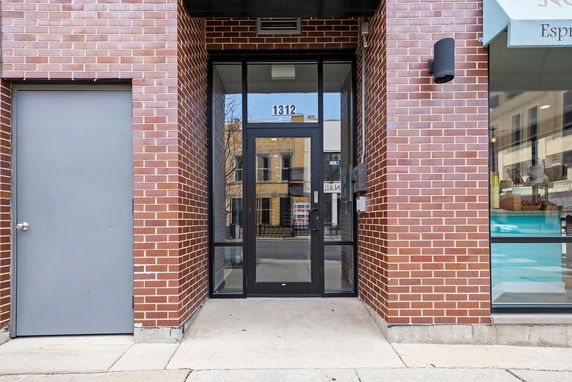 Front view of a building entrance with glass door and brick exterior.