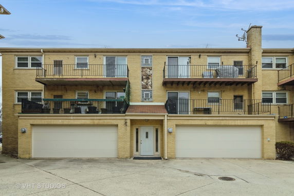 Front view of a two-story apartment building with balconies and a two-car garage.