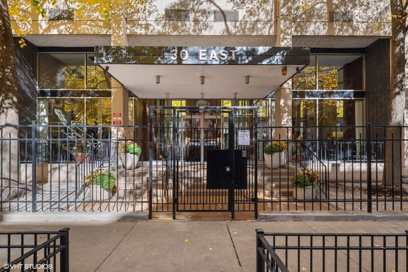 Front view of a building entrance with stairs and a metal gate.